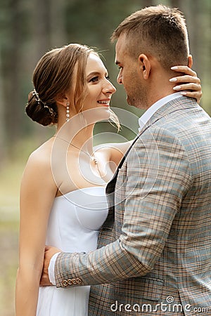 young couple bride in a white short dress and groom in a gray suit in a pine forest Stock Photo