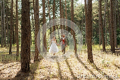 young couple bride in a white short dress and groom in a gray suit in a pine forest Stock Photo