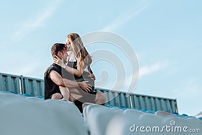 The girl sits on the guys lap and kisses his forehead Stock Photo