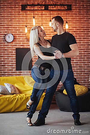 Young couple dancing latin music: Bachata, merengue, salsa. Two elegance pose on cafe with brick walls Stock Photo