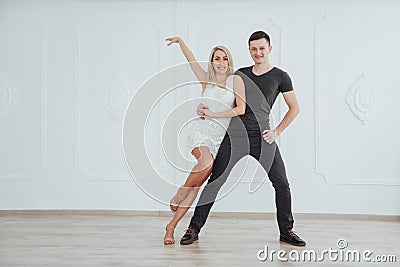 Young couple dancing latin music: Bachata, merengue, salsa. Two elegance pose on white room Stock Photo