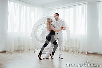 Young couple dancing latin music: Bachata, merengue, salsa. Two elegance pose on white room Stock Photo