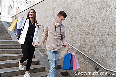 Young couple descending stairs with numerous packages after shopping Stock Photo