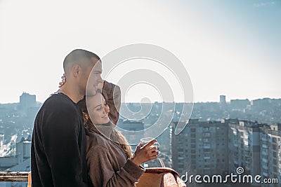 Young couple drinking coffee on the balcony of the apartment in the morning. Young happy couple, newlyweds family start Stock Photo