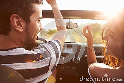 Young Couple Driving Along Country Road In Open Top Car Stock Photo