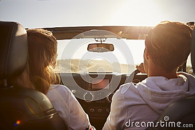 Young couple driving with sunroof open, rear passenger POV Stock Photo