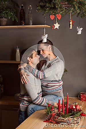 Young couple embracing gently and passionately kissing in the kitchen under the mistletoe on Christmas new year Stock Photo