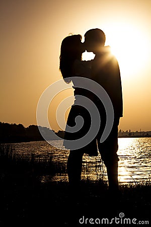 Young couple express their feelings in a kiss at dawn on nature Stock Photo