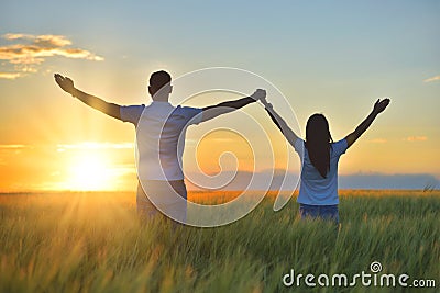 Young couple feeling free in a beautiful natural setting, in what field at sunset Stock Photo