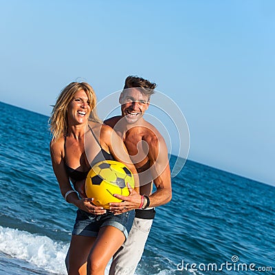 Young couple having fun with ball on beach. Stock Photo