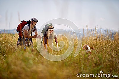 Young couple hiking in field, cudling with dog. Sport, freedom, holiday concept Stock Photo