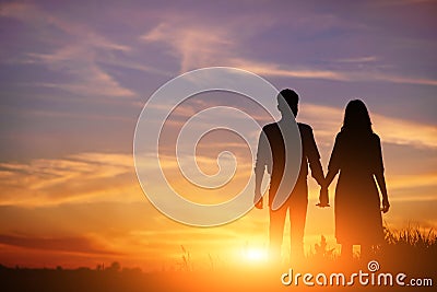 Young couple is holding hands on a background sunset silhouette Stock Photo