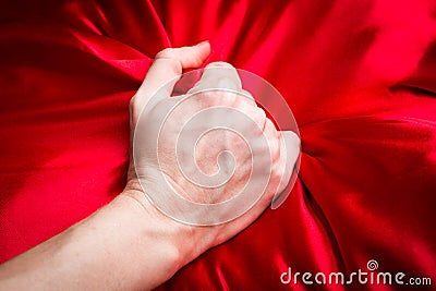 Young couple holding hands sensually on red silk bed Stock Photo