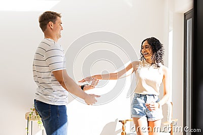 Young couple holding hands and smiling, enjoying time together indoors Stock Photo