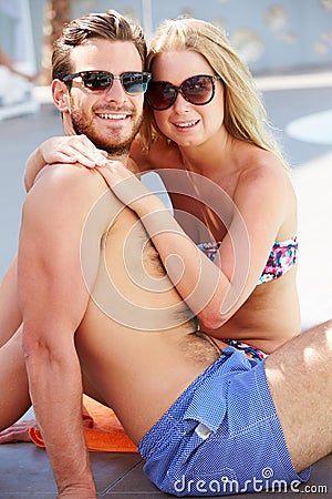 Young Couple On Holiday Relaxing By Swimming Pool Stock Photo