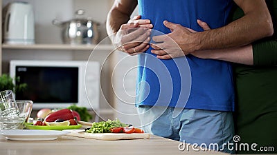 Young couple hugging during dinner preparation in kitchen, care and support Stock Photo