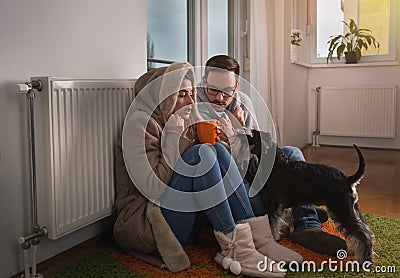 Couple with dog sitting beside radiator and freezing Stock Photo