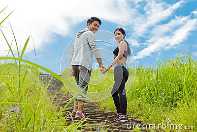 Couple jogging up stair in forest, holding hands together Stock Photo