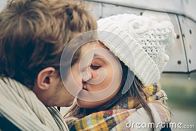 Young couple kissing outdoors under umbrella in a Stock Photo