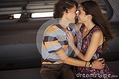 Young couple kissing in the summer daylight on a bridge construction in the city outdoors. copy space Stock Photo