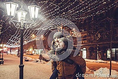 Young couple having fun under holiday winter illumination at night Stock Photo