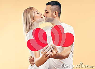 Young couple in love holding big paper hearts in hands over studio background Stock Photo