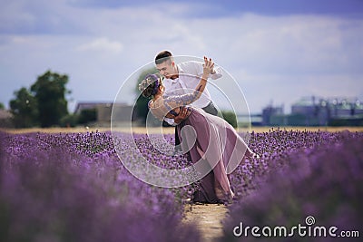 Young couple in love hugging and dancing in a lavender field on summer. girl in a luxurious purple dress Stock Photo