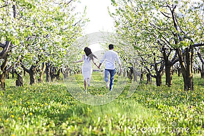 Young couple in love running in spring blossom garden Stock Photo