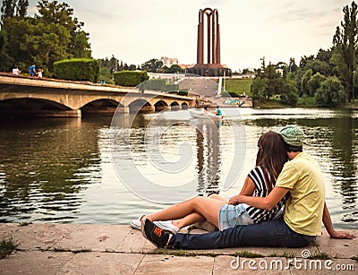 Young couple in love sitting near lake in park landscape Stock Photo