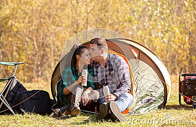 Young couple in love with thermos in hand kissing in front of the tent Stock Photo
