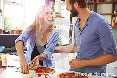 Young Couple Making Pizza In Kitchen Together Stock Photo