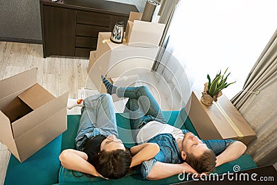 Young couple man and woman looking tired having break on the sofa during moving to new appartment unpacking boxes Stock Photo