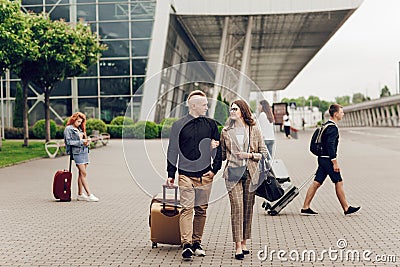 Young couple, man and woman near the airport with a suitcase. Happy couple traveling. Young people returning from a trip Stock Photo