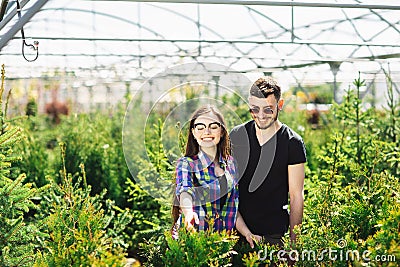 Young couple, man and woman, standing together in the garden center and choose plants for greening the house Stock Photo