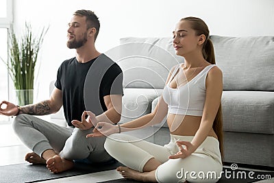 Young couple meditating together doing yoga at home on mat Stock Photo