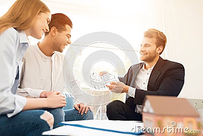 Young couple in a meeting with a realtor. Guy and girl make a contract with realtor buying property. Stock Photo