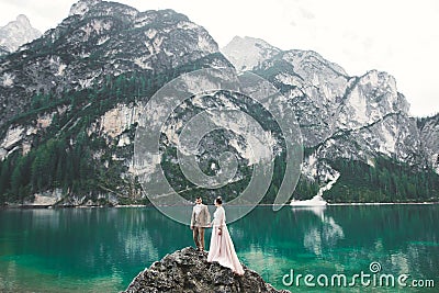 Young couple near lake Karersee, Italy. Holding hands at the stone at lake Stock Photo