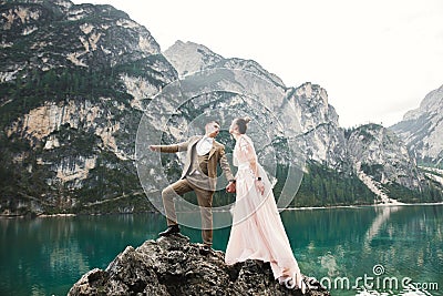 Young couple near lake Karersee, Italy. Holding hands at the stone at lake Stock Photo