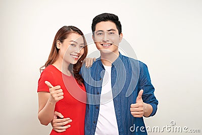 Young couple over isolated background smiling with happy face looking and pointing to the side with thumb up Stock Photo