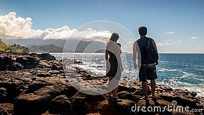 Couple overlooks the ocean off a rocky Kauai coast Stock Photo