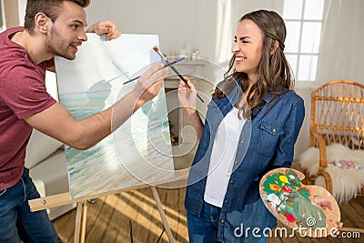 Young couple with paintbrushes having fun while painting together Stock Photo