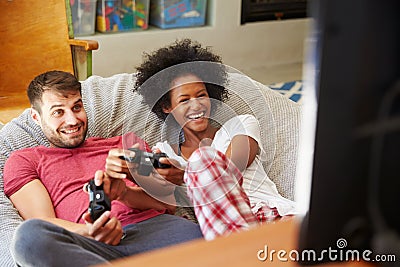 Young Couple In Pajamas Playing Video Game Together Stock Photo