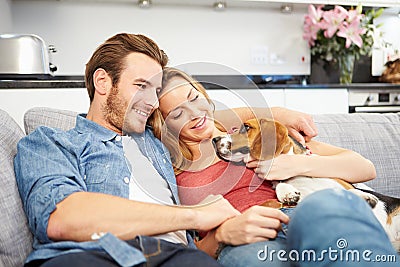 Young Couple Playing With Pet Dog At Home Stock Photo