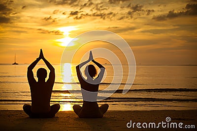 Young couple practicing yoga on beach at sunset Stock Photo