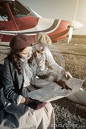 Young couple with private plane looking at map, vertical Stock Photo