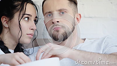 young couple reaching bowl while watching Stock Photo