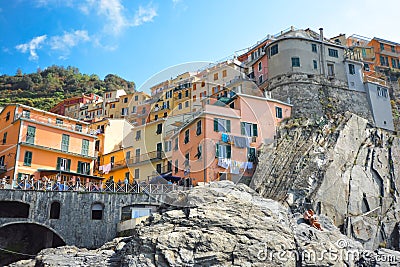 A young couple relaxes on the rocks above the swimming harbor of Manarola, Italy, Editorial Stock Photo