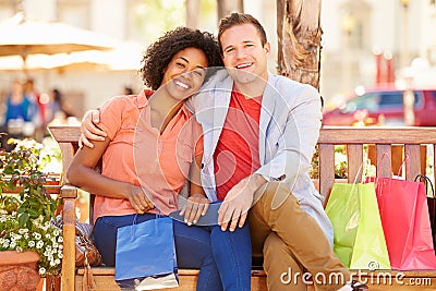 Young Couple Resting With Shopping Bags Sitting In Mall Stock Photo