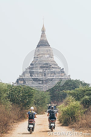 Young couple riding electric scooter towards Shwesandaw pagoda of ancient Bagan in Myanmar Editorial Stock Photo