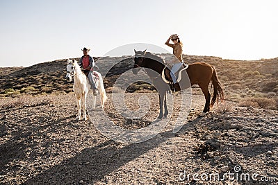 Young couple riding horses doing excursion at countryside during sunset time - Main focus on woman face Stock Photo